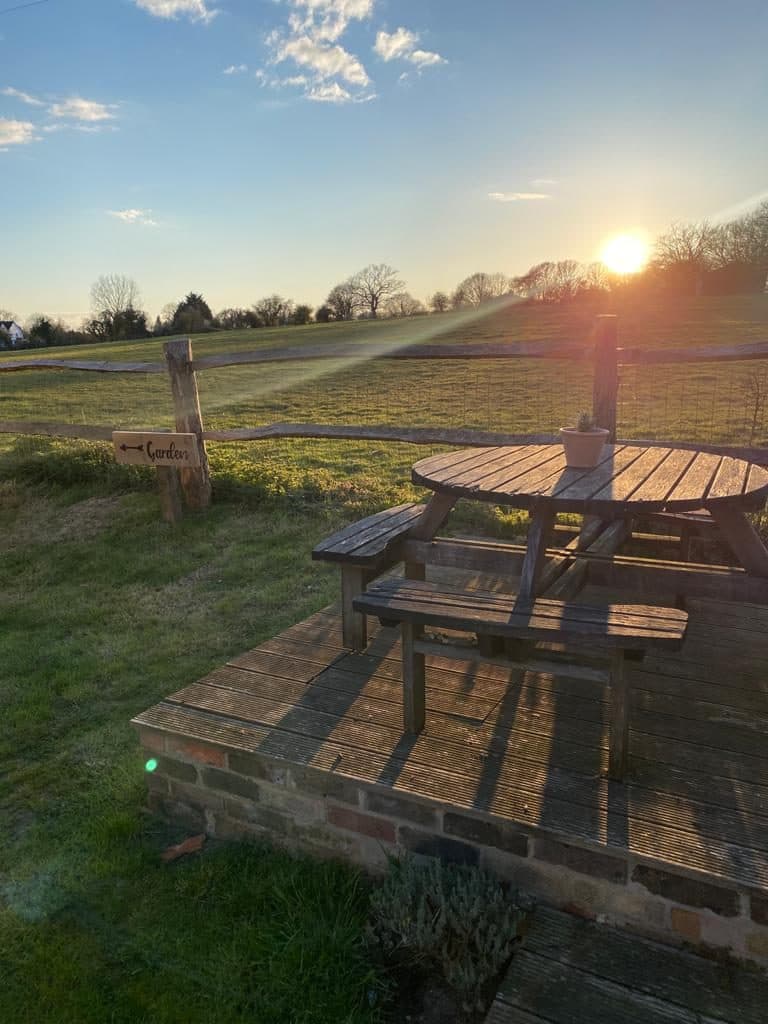 Beer garden picnic table on the decking, looking out over open fields at sunset