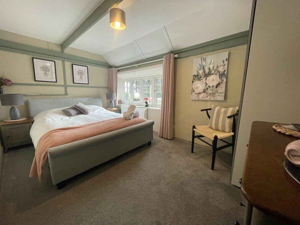 Bright guest bedroom with grey upholstered bed and soft pink throw